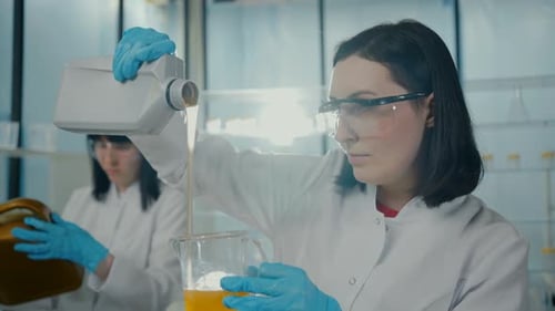 Women Scientists Pouring Liquid into Beaker in Laboratory
