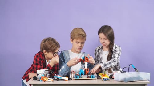 Portrait of Clever Children Assembling Robots on Table, Teamwork
