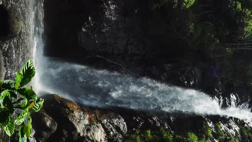 Tropical Waterfall Cascading Down Lush Rock Cliff