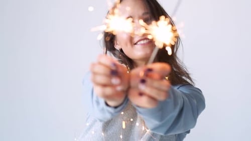 Happy Woman Holds Sparklers in White Studio