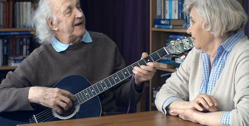 Senior Man Plays Guitar and Sings to Wife