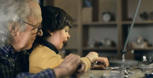 Grandfather and Child Repairing a Watch Together Indoors