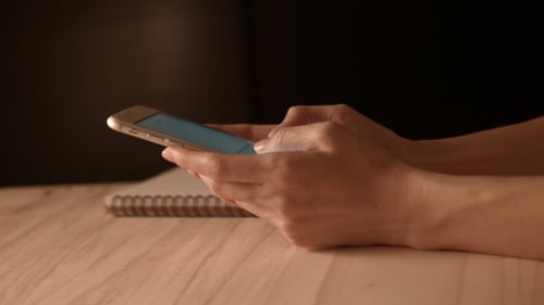 Fingers Touching Cell Phone Touchscreen at Table
