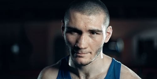 Sweaty Male Boxer Trains Hard in Dark Gym