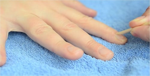 Hand Pushing Back Cuticles with Wooden Stick