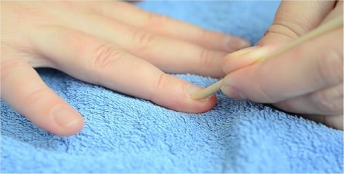 Manicurist Pushing Back Cuticles with Wooden Stick