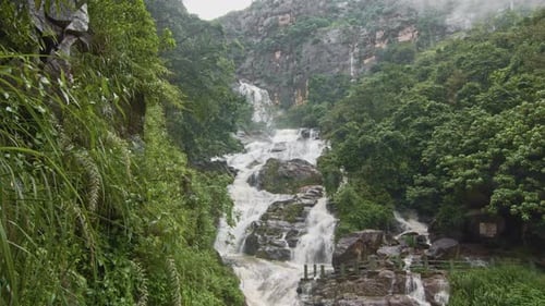 Lush Tropical Waterfall Cascading Down Mossy Rocks