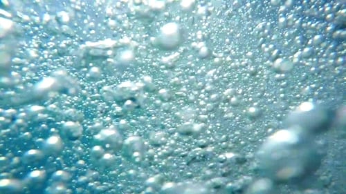 Blasen in frischem blauem Wasser im Schwimmbad