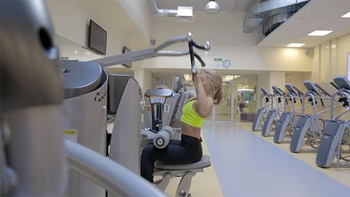Woman Exercises at Gym on Pulldown Machine