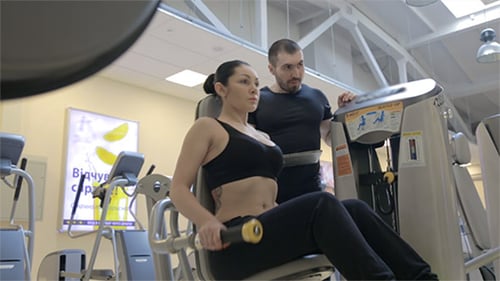 Woman Works Out with Trainer in Gym