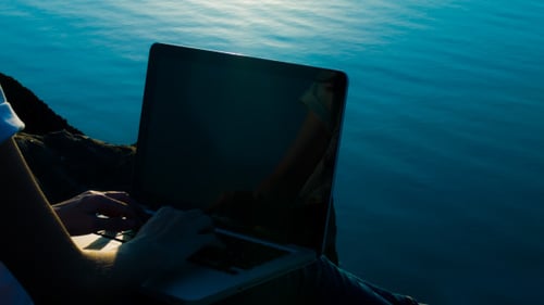 Typing on Laptop By Reflective Lake At Sunset