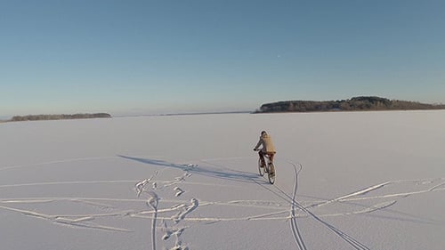 Person Rides Bicycle Across Snowy Landscape
