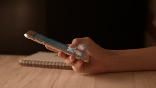 Person Interacting with Smartphone Next to Notebook