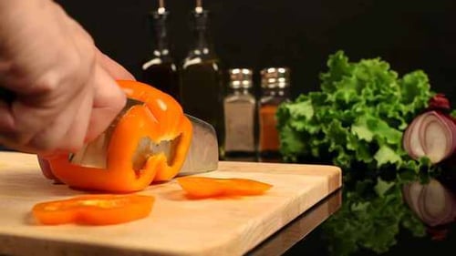Slicing Fresh Orange Bell Pepper on Cutting Board