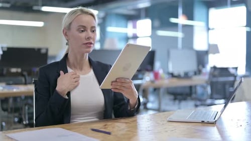 Attractive Businesswoman Doing Video Chat on Tablet in Office