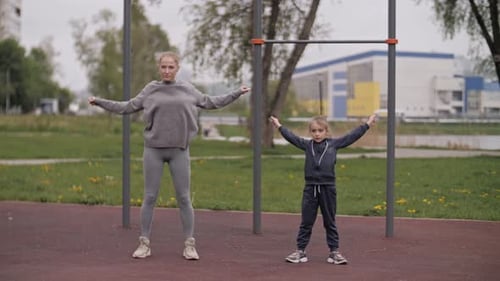 Mother and Daughter Doing Exercises on Open Air Sport Playground