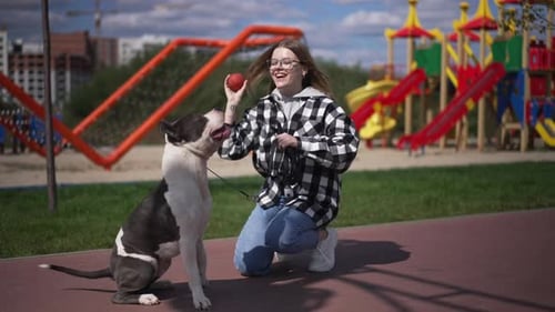 Young Woman Playing with Dog in Urban Park