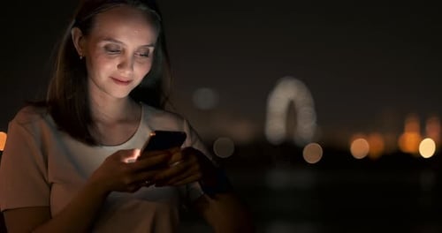 Woman Looks At Phone At Night In City