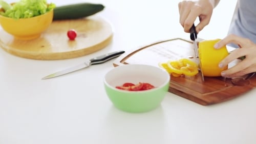 Woman Cuts Yellow Pepper in Bright Kitchen