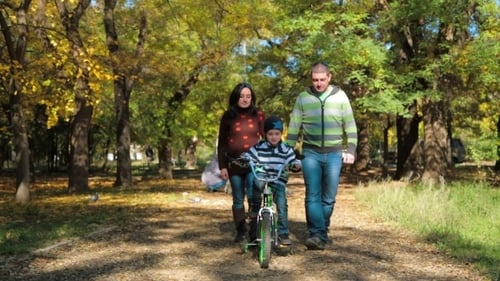 Family Walk With Young Boy Riding Bike in Autumn Park