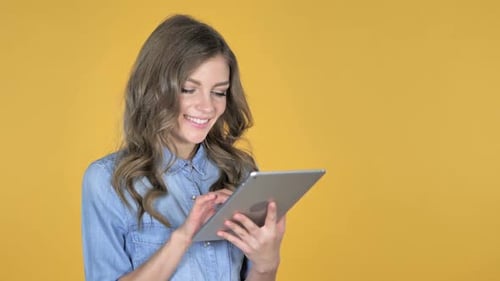 Woman Using Tablet Device Against Yellow Background