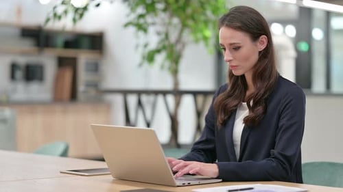 Woman Typing on Laptop in Bright Modern Office