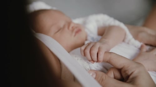 Infant Sleeping Soundly, Parent Gently Holds Hand