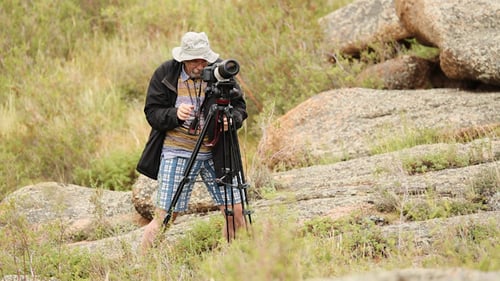 Man Using Camera with Tripod Outdoors