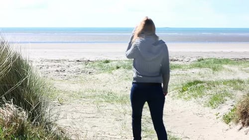 Woman Walking On A Beach In Windy Weather