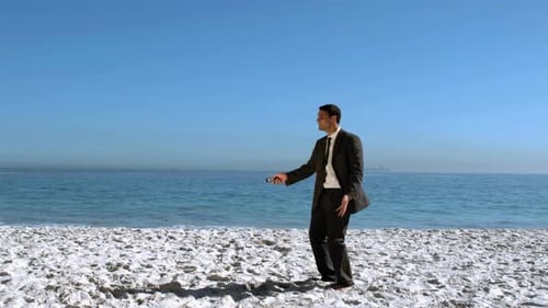 Businessman Throwing His Mobile In The Air On The Beach