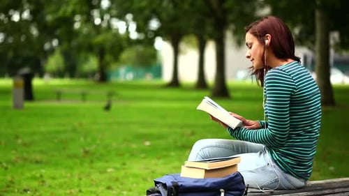 Young Woman Reading Book on Bench in Park