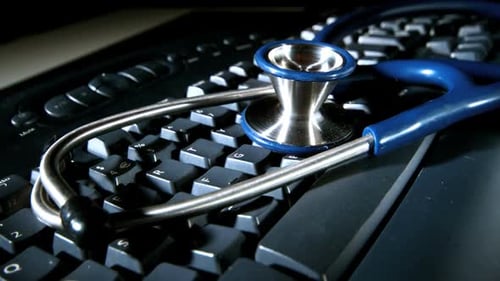 Stethoscope Lying on Black Computer Keyboard Close Up