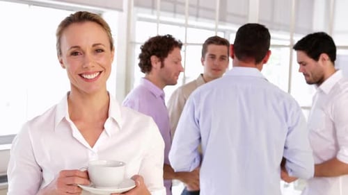 Smiling Woman Holds Coffee, Men Talking in Office