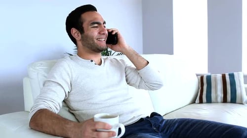 Young Adult Talking on Cellphone While Relaxing Indoors