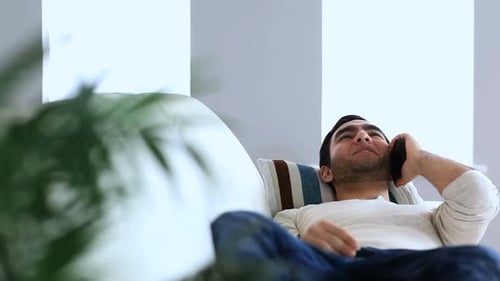 Man Talking on Cellphone Relaxing on a Sofa