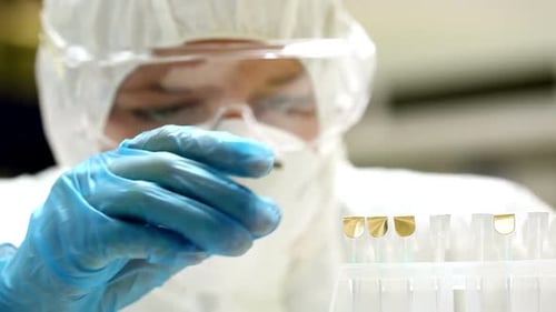 Science Student In Protective Suit Comparing Samples