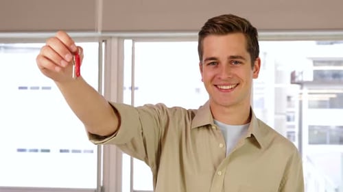 Young Man Smiling Holding Keys Indoors
