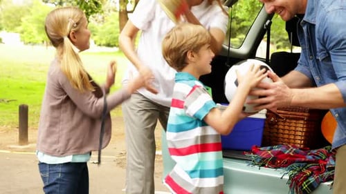 Family Unpacks Camping Gear in Sunny Park