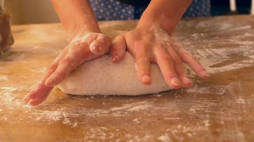 Female Hands Kneading Ball Of Dough On A Floury Surface