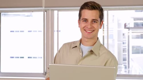 Smiling Young Adult with Laptop in Modern Office