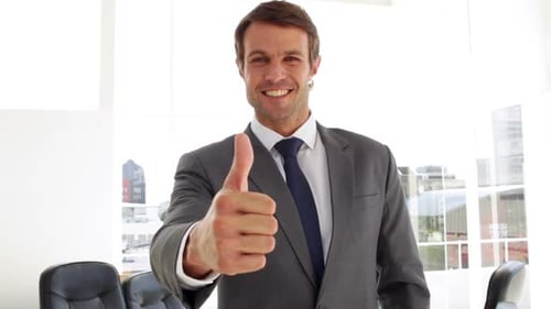 Smiling Businessman Gives Thumbs Up in Bright Office