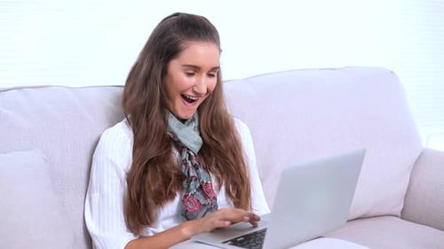 Woman Uses Laptop Comfortably on Sofa At Home