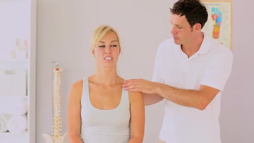 Patient receiving shoulder examination in brightly lit clinic