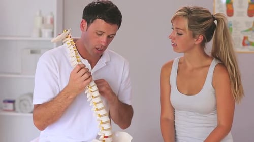 Chiropractor Explains Spine Model to Woman Patient