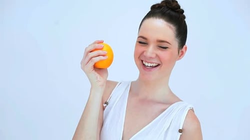 Smiling Woman Holding an Orange in Studio
