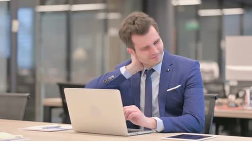 Businessman Having Neck Pain While Using Laptop in Office
