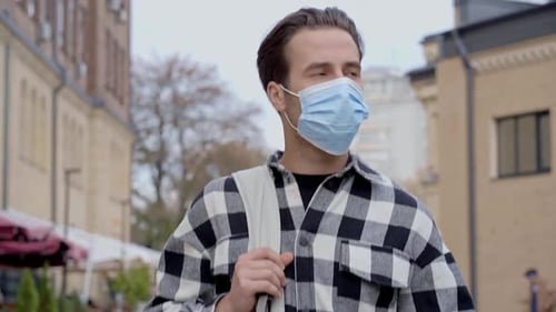 Man Walks on City Sidewalk Wearing Face Mask