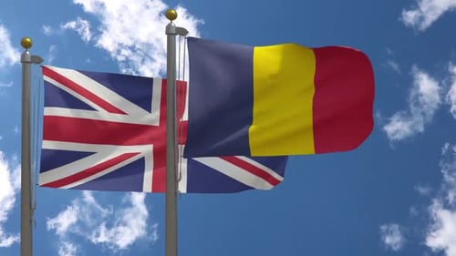 United Kingdom and Belgium Flags Waving Against Blue Sky
