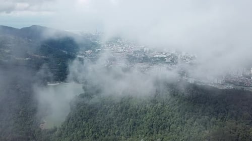 Aerial fly over foggy sky above Ayer Itam dam