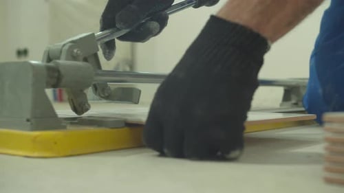 Close Up, Man in Protective Gloves Cuts a Tile